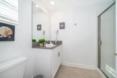 a white bathroom with a shower and a toilet at 4415RH TOWNHOUSE 5 BEDROOMS & 4 BATHROOMS + POOL in Kissimmee