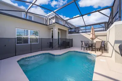 a swimming pool with a table and chairs in a house at 4415RH TOWNHOUSE 5 BEDROOMS & 4 BATHROOMS + POOL in Kissimmee
