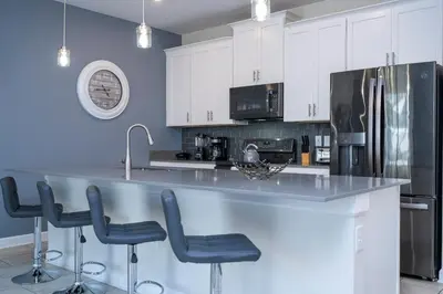 a kitchen with white cabinets and a large counter with stools at 4337 QS - Charming Hideaway in Kissimmee