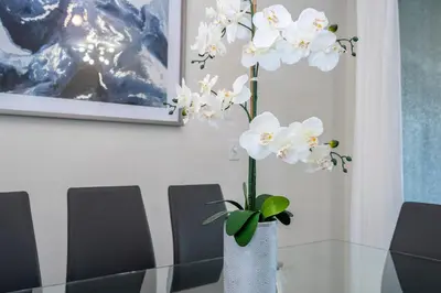 a white vase with white flowers on a glass table at 4337 QS - Charming Hideaway in Kissimmee