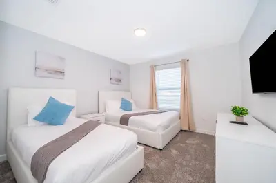 a bedroom with two beds and a tv and a couch at 4435LT TOWNHOUSE 4 BEDROOMS & 3 BATHROOMS + POOL in Kissimmee