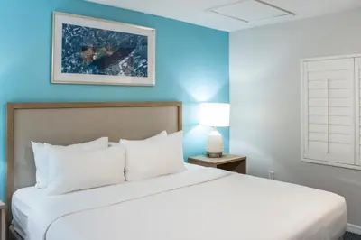 a bedroom with a white bed with a blue wall at Barefoot'n Resort Kissimmee Orlando in Orlando