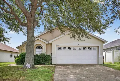 a house with a tree and a garage at Luxury 4-Bedroom Home with Private Pool, Jacuzzi, AC, Wi-Fi, Cable TV, 5 Minutes from Disney in Kissimmee