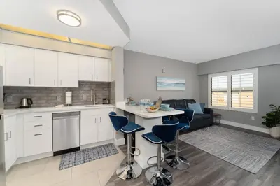 a kitchen and living room with white cabinets and blue stools at Cozy Orlando Getaway with Pool Access in Orlando