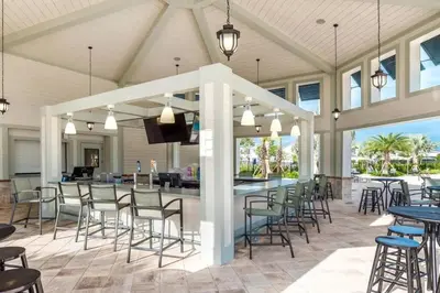 a covered patio with tables and chairs and a bar at Dream Vacation Home with Lake View, Pool, more, and Walking Distance to Resort in Kissimmee