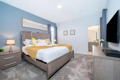 a bedroom with a large bed and a flat screen tv at 4338JE VILLA 5 BED/5 BA in Kissimmee