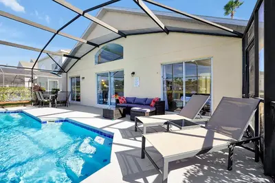 a house with a swimming pool and a patio at Lake Berkley Home: Pool, Lakefront & near Disney in Kissimmee