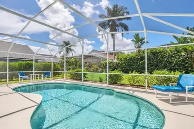 a swimming pool with two chairs and a table at 10 Min from Disney Themed 2 Bd Private Pool in Orlando