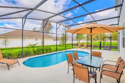 a patio with a table and an umbrella and a pool at Home w Pool & Games Room Near Disney -Pet Friendly in Kissimmee