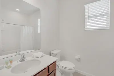 a white bathroom with a toilet and a sink at Home w Pool & Games Room Near Disney -Pet Friendly in Kissimmee