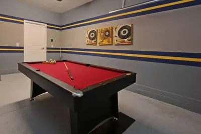 a pool table in a room with a red cover at Spacious 6 Bed Home with Pool in Prime Storey Lake Location in Kissimmee