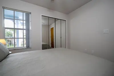 a white bedroom with a large bed and a window at Family Apt very close to Disney in Kissimmee