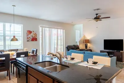 a kitchen and living room with a sink and a couch at Luxury 4 bedroom 3 bath pool Home 283 in Kissimmee
