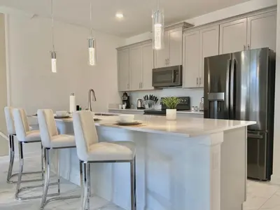 a kitchen with a large island with chairs and a refrigerator at Beautiful 4 bedroom 3 bath pool Townhome 280 in Kissimmee