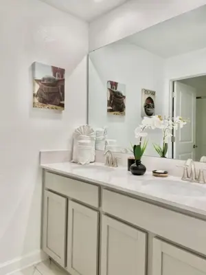 a white bathroom with two sinks and a mirror at Luxury 4 bedroom 3 bath pool Home 264 in Kissimmee