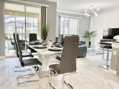 a dining room with a white table and chairs at Luxury 4 bedroom 3 bath pool Home 264 in Kissimmee