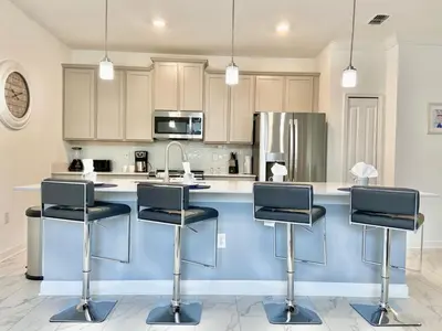 a kitchen with a blue island with three bar stools at Luxury 4 bedroom 3 bath pool Home 264 in Kissimmee