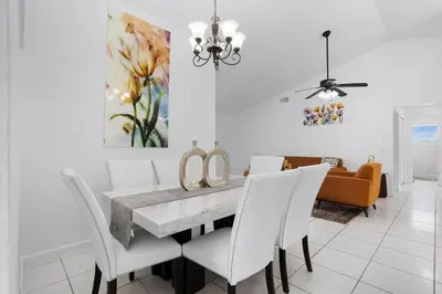 a dining room with a table and white chairs at APluSS Getaway in Kissimmee