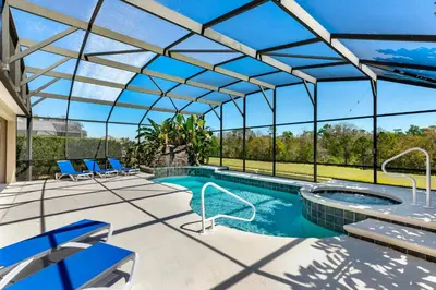 a pool with blue chairs and a large glass roof at Luxury Emerald Island Resort Villa with Stunning Pool Deck and Lake View Near Disney in Kissimmee
