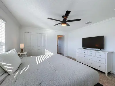 a bedroom with a bed with a ceiling fan and a television at Incredible Family Retreat with PS5 Private Pool and access to 2 Clubhouses in Kissimmee