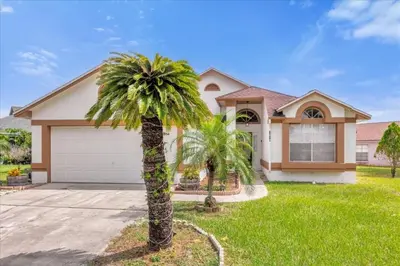 a palm tree in front of a house at Cozy Home Near Disney With Private Pool in Kissimmee