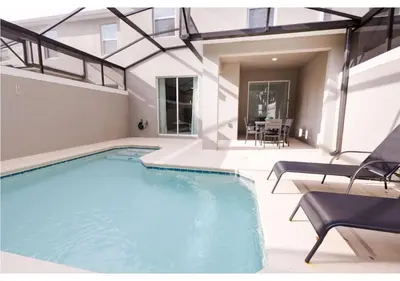 a swimming pool with two chairs and a table at 2489 RT Ultimate Villa Oasis with Pool & Spa Sleeps 13 in Kissimmee