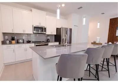 a kitchen with white cabinets and bar stools at 2489 RT Ultimate Villa Oasis with Pool & Spa Sleeps 13 in Kissimmee