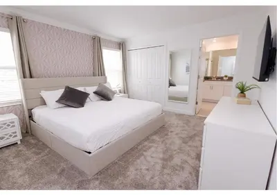 a white bedroom with a bed and a mirror at 2489 RT Ultimate Villa Oasis with Pool & Spa Sleeps 13 in Kissimmee