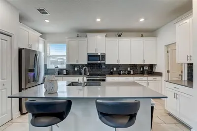 a large kitchen with white cabinets and a large island at 2940 - Elegant 5BR Villa at Storey Lake Resort Comfort Luxury and Proximity Disney and Universal in Kissimmee