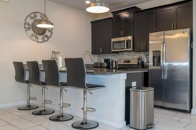 a kitchen with a stainless steel refrigerator and black cabinets at Opulent 5 BR Villa Private Pool - 12 Guests - 3085 TS in Kissimmee