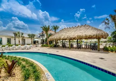 a resort pool with chairs and a straw umbrella at Luxury 3-Bed Condo in Storey Lake Resort - 3131 in Kissimmee