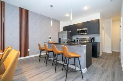 a kitchen with a bar with chairs and a counter at 3258 SW - Luxury Getaway The Hub Relax and Enjoy a Serene Vacation Retreat in Kissimmee