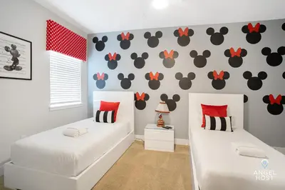 two beds in a room with a wall with mouse decals at Palatial 9BR Private Pool Villa Theater Game Room in Orlando