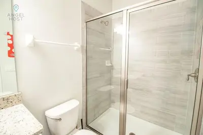 a bathroom with a toilet and a glass shower at Palatial 9BR Private Pool Villa Theater Game Room in Orlando
