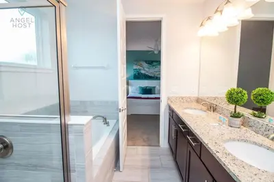 a white bathroom with two sinks and a shower at Palatial 9BR Private Pool Villa Theater Game Room in Orlando