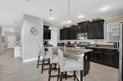 a kitchen with black cabinets and a kitchen island with bar chairs at 9008 Paradise Palms Blissful Haven 5-Bed Oasis of Luxury and Tranquility in Orlando