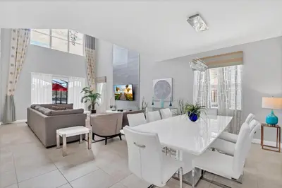 a dining room and living room with a white table and chairs at 9008 Paradise Palms Blissful Haven 5-Bed Oasis of Luxury and Tranquility in Orlando