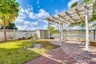 a pergola in a yard with a fence at Furnished Lanai and Lake View Quiet Home in Orlando in Kissimmee