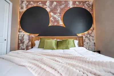 a bedroom with a large white bed with a brick wall at The Mouse PlayHouse in Orlando