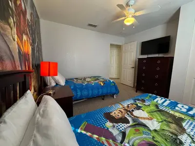a bedroom with two beds and a flat screen tv at 4 Bedroom 3 Bathroom Villas At SevenDwarfs 28-107 in Kissimmee