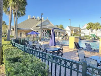 a fence with tables and chairs and a pool at 4 Bedroom 3 Bathroom Villas At SevenDwarfs 28-107 in Kissimmee