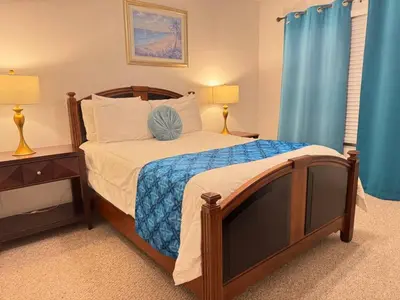 a bedroom with a bed with a tv and blue curtains at 4 Bedroom 3 Bathroom Villas At SevenDwarfs 22-108 in Kissimmee