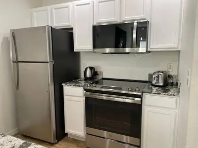 a kitchen with white cabinets and a stainless steel refrigerator at 3 Bedroom 2 Bathroom Villas At SevenDwarfs 15-103 in Kissimmee