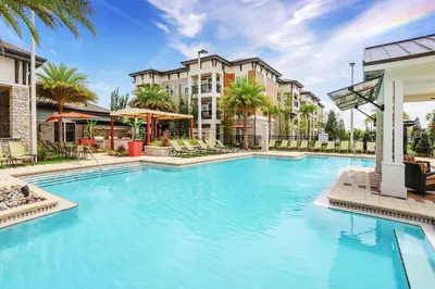 a large swimming pool with palm trees and buildings at Chic 1-Bedroom Apt in Lake Nona in Orlando