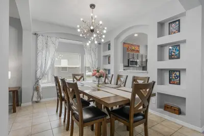 a dining room with a table and chairs and a chandelier at La Isla Retreat - amazing 6 bedroom pool house near Disney Parks in Kissimmee