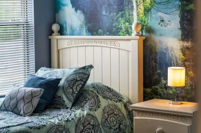 a bedroom with a bed with a lamp on a table at La Isla Retreat - amazing 6 bedroom pool house near Disney Parks in Kissimmee