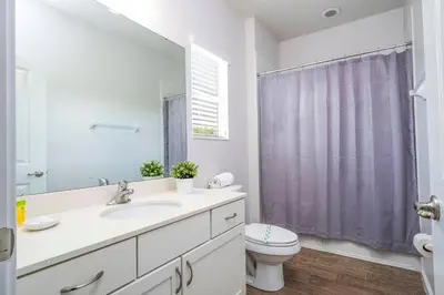 a bathroom with a sink and a toilet and a mirror at Luxury Lakeview Home Private Pool 2687 in Kissimmee