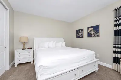 a white bedroom with a white bed and a nightstand at Spacious Home With Private Pool, Themed And Game Room Near Disney With Waterpark & Resort Access - 341Pn in Kissimmee