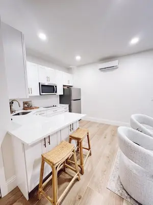 a kitchen with a white counter and two stools at Modern Guesthouse near MCO in Kissimmee