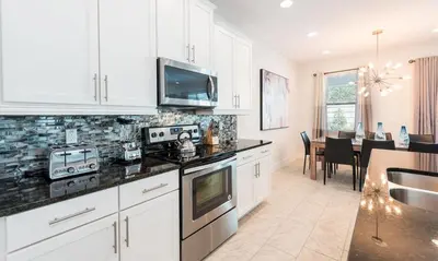 a kitchen with white cabinets and black counter tops at Luxury Private Villa with Large Pool on Encore Resort at Reunion Orlando Villa 4433 in Orlando
